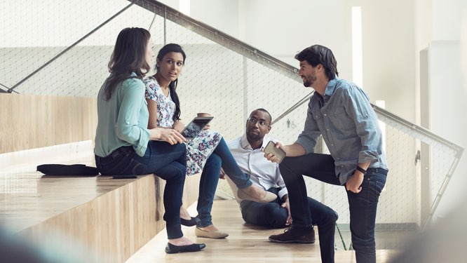 four business professionals in a casual discussion setting